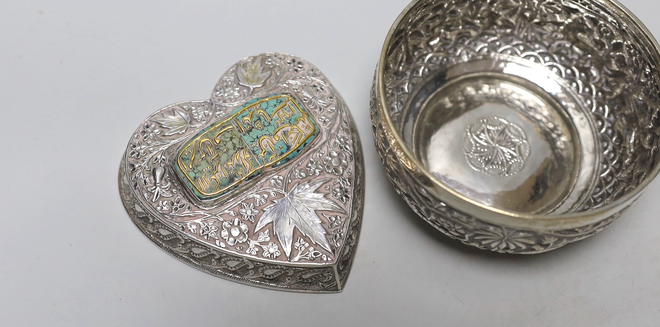 A pair of Indian embossed white metal finger bowls, diameter 97mm , a Persian white metal and turquoise set heart shaped paperweight and an Indian white metal and turquoise set heart shaped box.